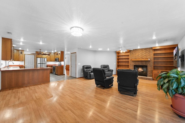 living room featuring visible vents, a fireplace, a textured ceiling, and light wood-type flooring