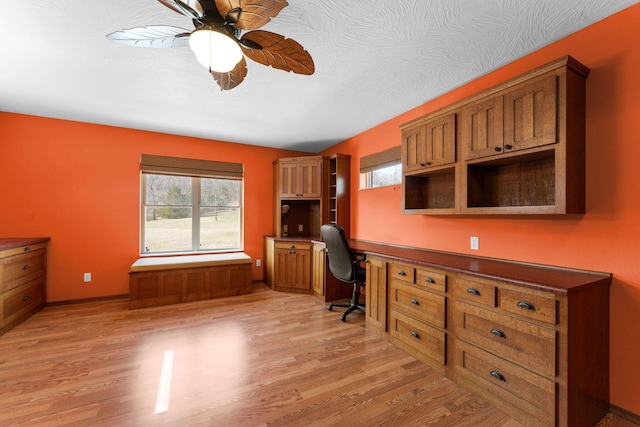 office featuring ceiling fan, light wood-style floors, baseboards, and built in study area