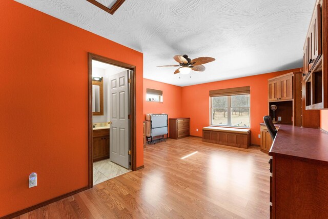 interior space featuring a ceiling fan, light wood-style floors, and a textured ceiling