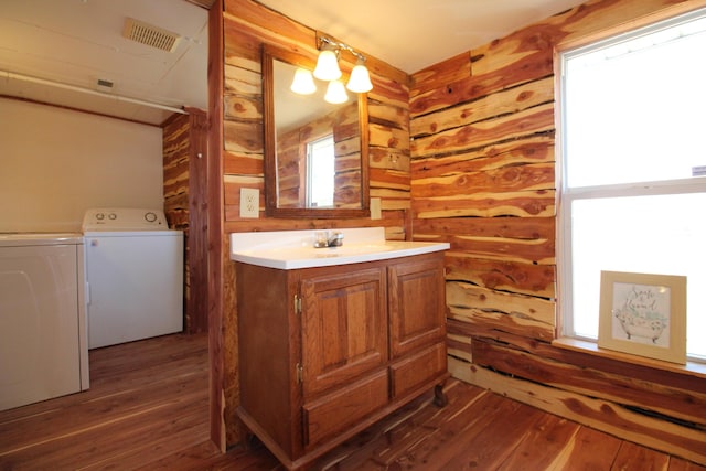 bathroom featuring visible vents, hardwood / wood-style floors, separate washer and dryer, wood walls, and vanity