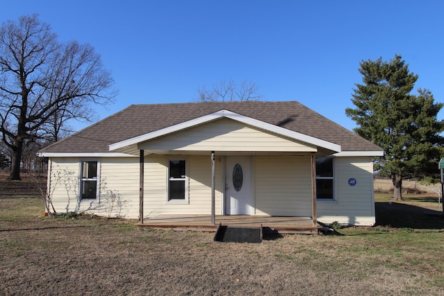 view of front of home with covered porch, a shingled roof, and a front yard