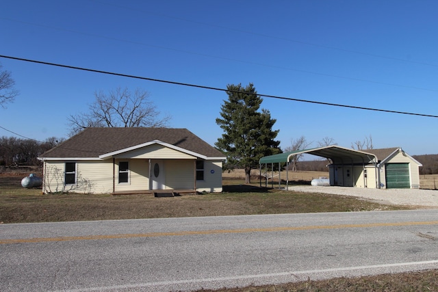 bungalow-style house with a garage, a carport, driveway, and a shingled roof