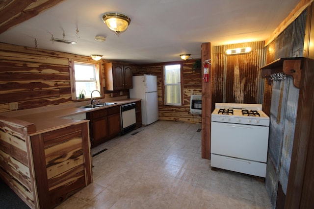 kitchen featuring visible vents, wood walls, white appliances, and a sink