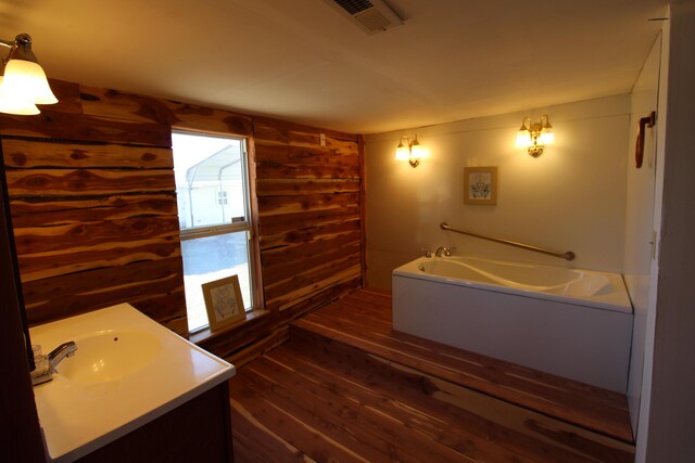 full bathroom with visible vents, a garden tub, wood finished floors, wood walls, and vanity