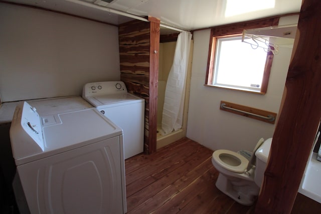 clothes washing area with independent washer and dryer, wood finished floors, and laundry area