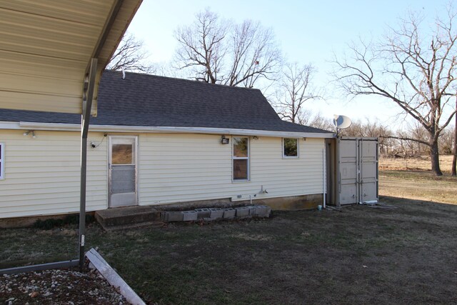 rear view of property featuring a yard and a shingled roof