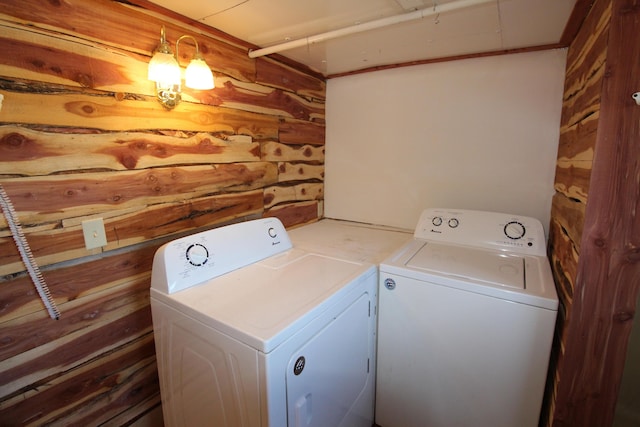 clothes washing area featuring laundry area, wooden walls, and washing machine and clothes dryer