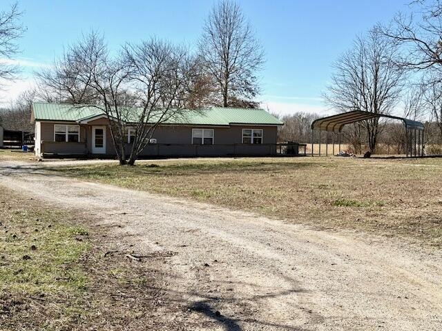 view of front of house featuring a carport, metal roof, a front lawn, and dirt driveway