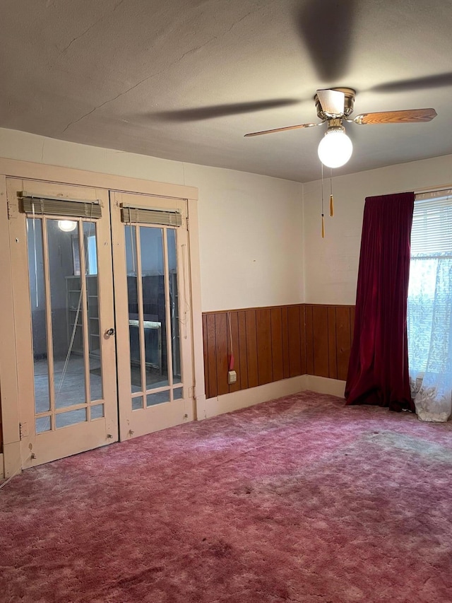 104 N High St, Neosho, MO 64850 - spare room with wooden walls, carpet, wainscoting, french doors, and a ceiling fan