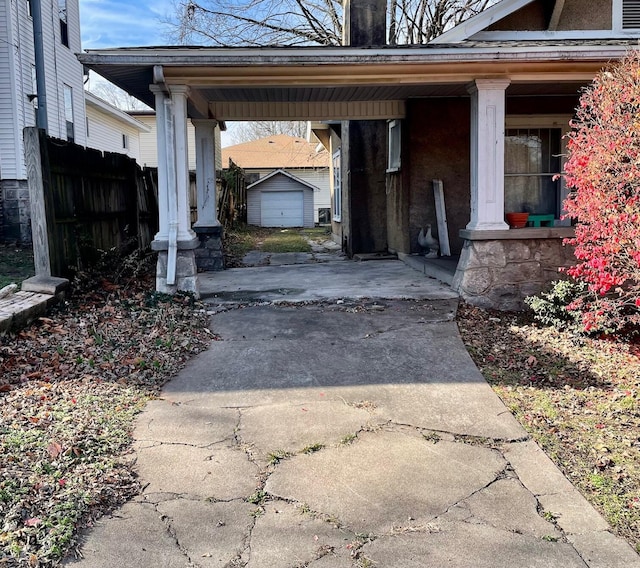 104 N High St, Neosho, MO 64850 - exterior space featuring a carport, fence, a porch, concrete driveway, and an outbuilding