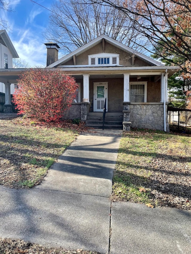 104 N High St, Neosho, MO 64850 - view of front facade with stone siding, a porch, and a chimney