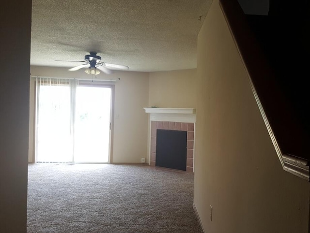 unfurnished living room featuring a textured ceiling, a ceiling fan, carpet floors, and a tile fireplace