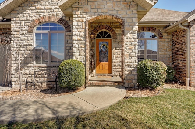 doorway to property featuring stone siding and a shingled roof