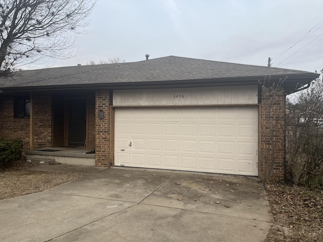 view of front of house with concrete driveway, a garage, brick siding, and a shingled roof