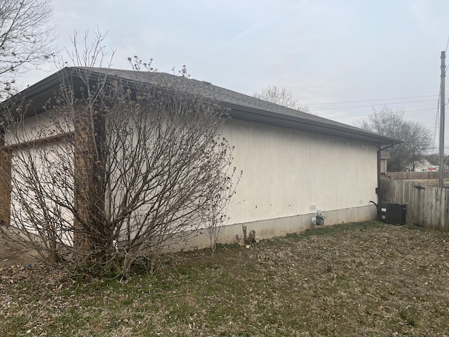 view of side of home with central AC unit and fence