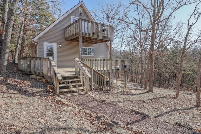 back of house featuring a balcony and a wooden deck