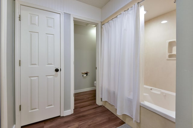 full bath featuring baseboards, toilet, wood finished floors, and shower / bath combination with curtain