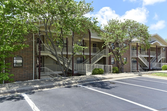 view of property featuring stairway and uncovered parking