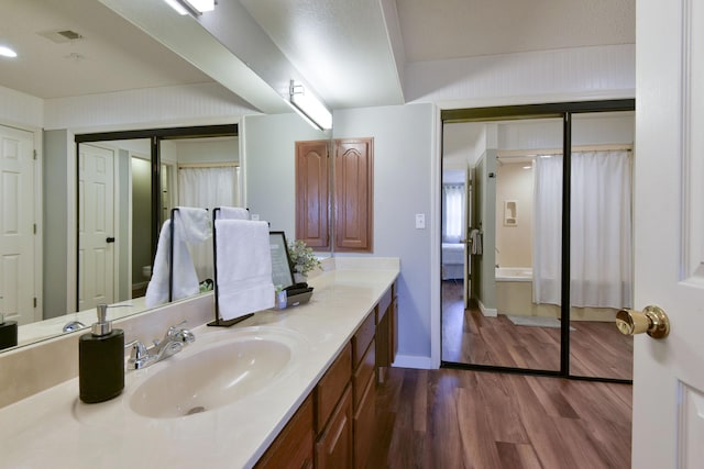 bathroom with visible vents, vanity, baseboards, and wood finished floors