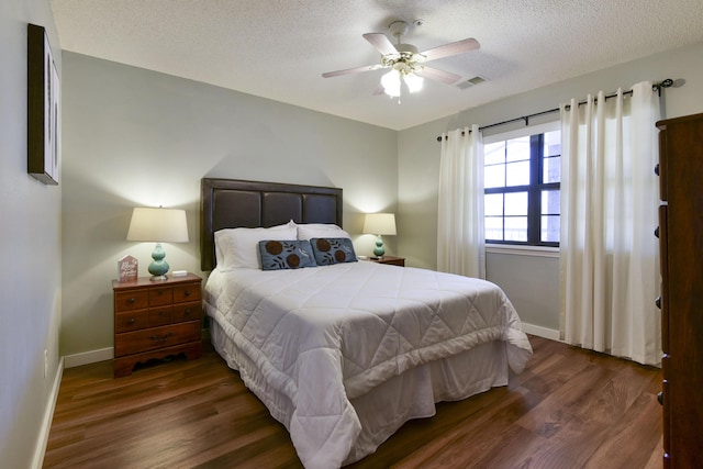 bedroom with visible vents, baseboards, a textured ceiling, and wood finished floors