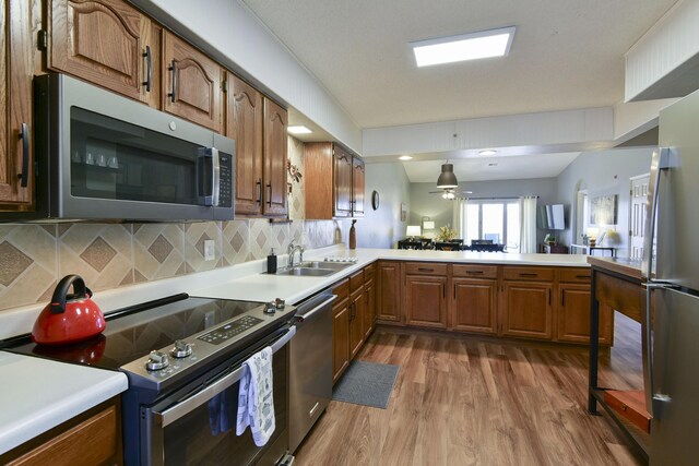 kitchen with appliances with stainless steel finishes, light countertops, a peninsula, and a sink