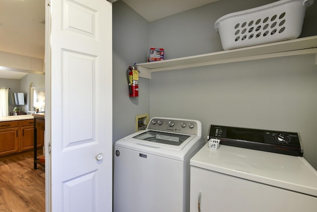 clothes washing area featuring light wood-style floors, independent washer and dryer, and laundry area