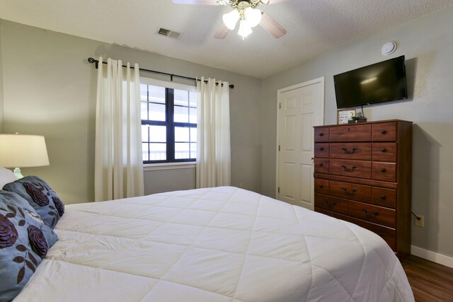 bedroom featuring visible vents, a ceiling fan, a textured ceiling, wood finished floors, and baseboards