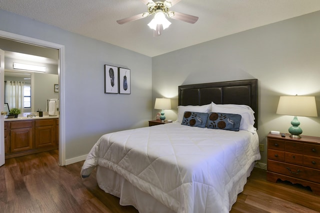 bedroom featuring a sink, ensuite bath, dark wood-style floors, baseboards, and ceiling fan