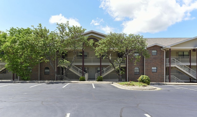 view of building exterior featuring stairway and uncovered parking