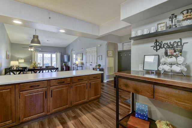 kitchen featuring open shelves, arched walkways, dark wood-style flooring, light countertops, and brown cabinets