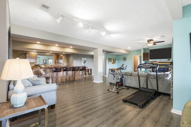 exercise room featuring visible vents, a ceiling fan, wood finished floors, baseboards, and indoor bar