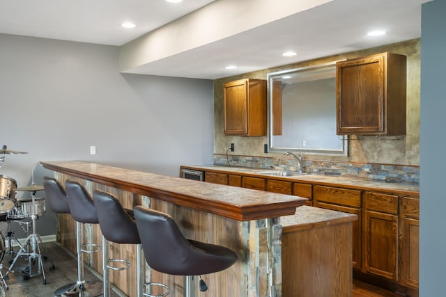 kitchen featuring decorative backsplash, a kitchen breakfast bar, dark wood-style flooring, and a sink