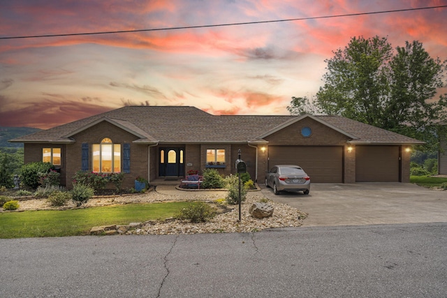 ranch-style house with brick siding, a garage, driveway, and a shingled roof