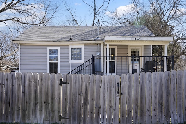 view of front of property featuring a fenced front yard, covered porch, a shingled roof, and a gate