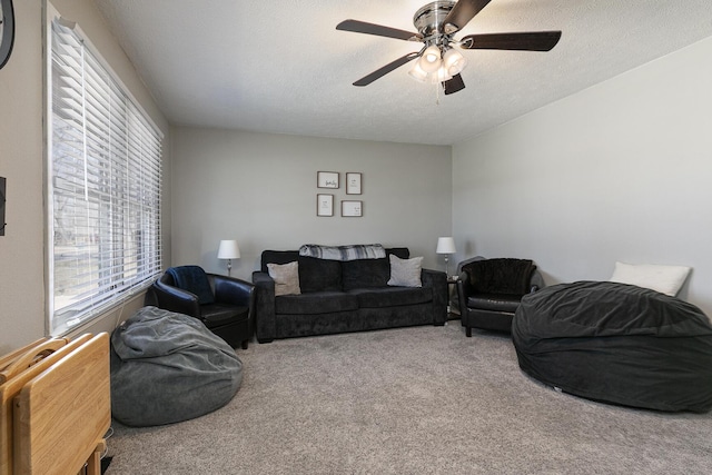 carpeted living room featuring ceiling fan and a textured ceiling