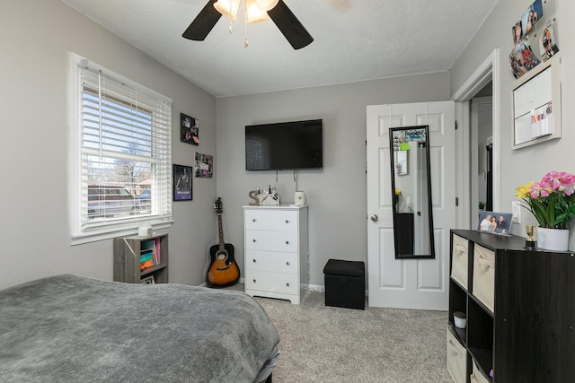 carpeted bedroom with ceiling fan and a textured ceiling