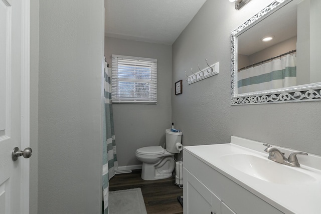 full bathroom with toilet, vanity, wood finished floors, a textured wall, and a textured ceiling