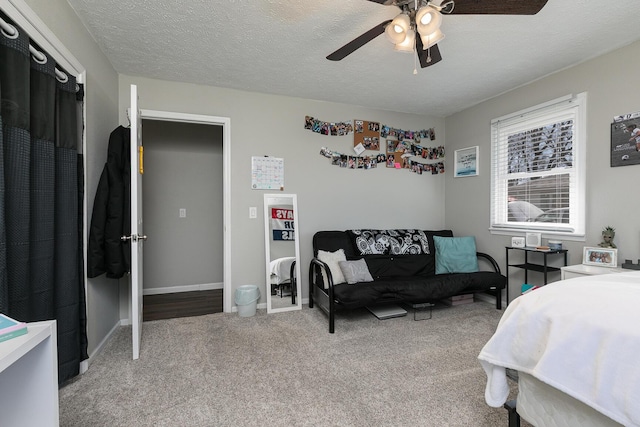 carpeted bedroom featuring baseboards, a textured ceiling, and a ceiling fan