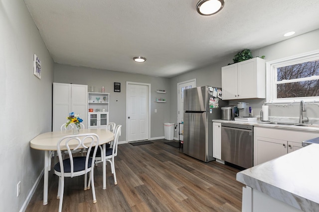 kitchen with dark wood-style flooring, a sink, light countertops, appliances with stainless steel finishes, and white cabinetry