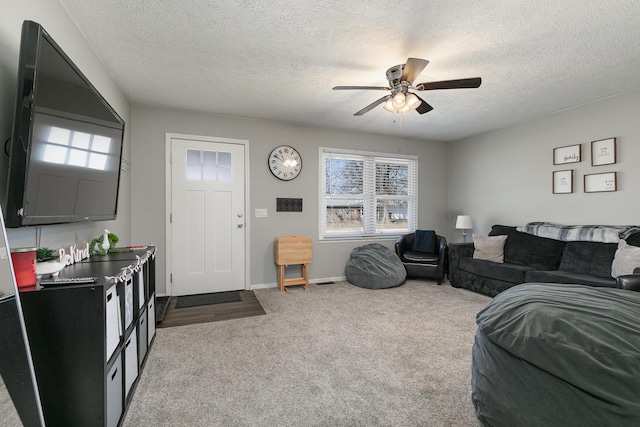 carpeted living room featuring a textured ceiling, baseboards, and a ceiling fan