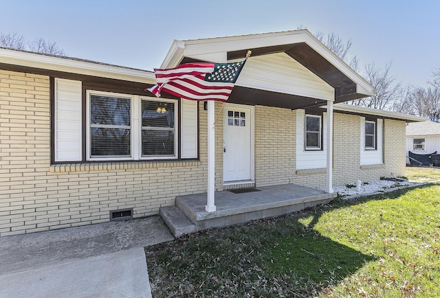 view of front facade featuring brick siding, crawl space, and a front lawn