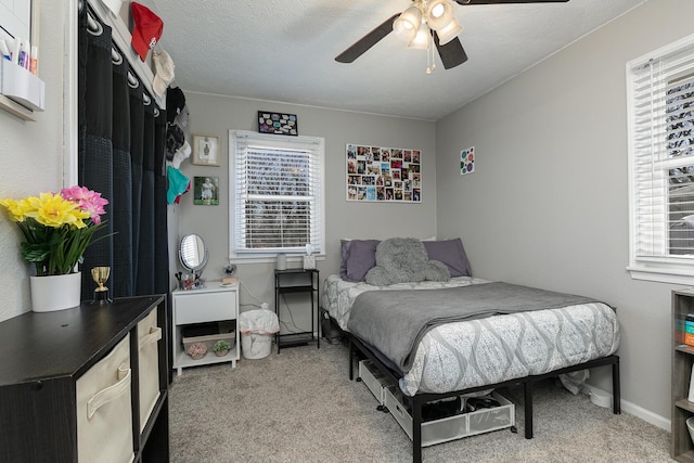 bedroom with multiple windows, a textured ceiling, and light colored carpet