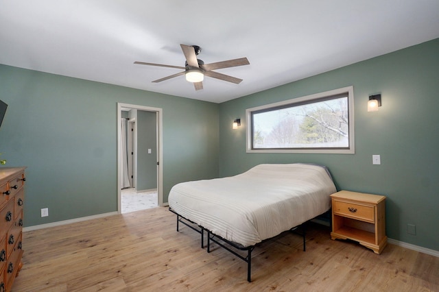 bedroom with a ceiling fan, baseboards, and light wood finished floors