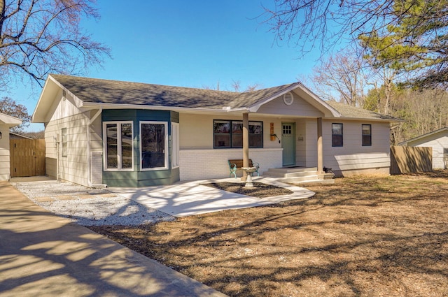 ranch-style house featuring fence, brick siding, and a shingled roof