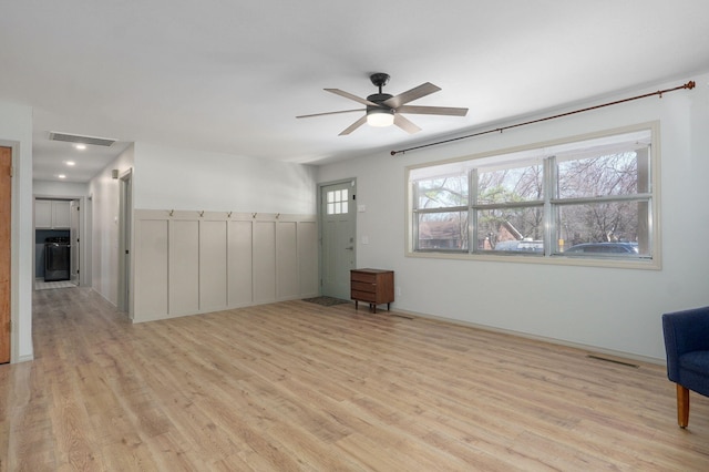 unfurnished living room featuring a ceiling fan, visible vents, and light wood finished floors