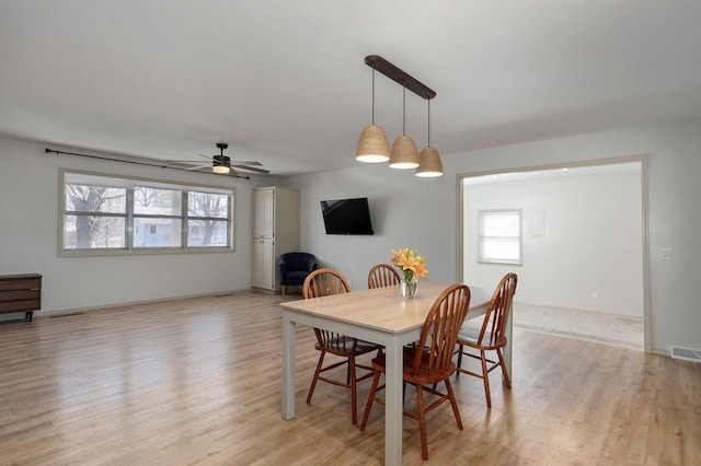 dining room with a healthy amount of sunlight, light wood-type flooring, and baseboards