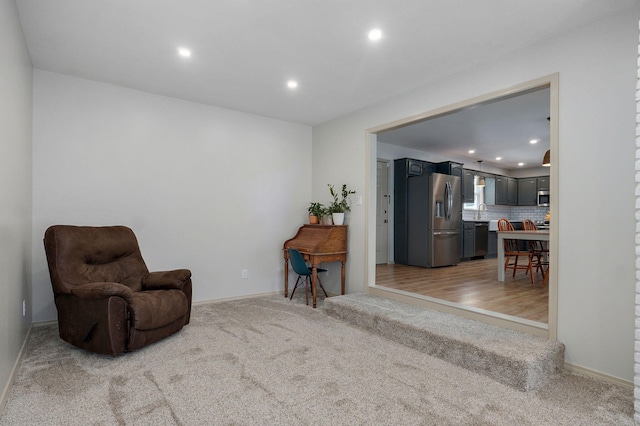 sitting room featuring recessed lighting, baseboards, and light carpet