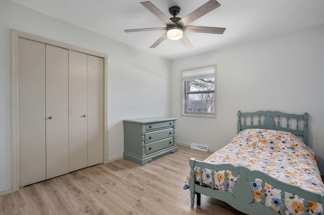 bedroom featuring baseboards, visible vents, light wood-style flooring, ceiling fan, and a closet