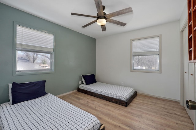 bedroom featuring light wood finished floors, ceiling fan, and baseboards