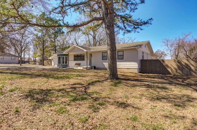 rear view of house with fence, a lawn, and crawl space